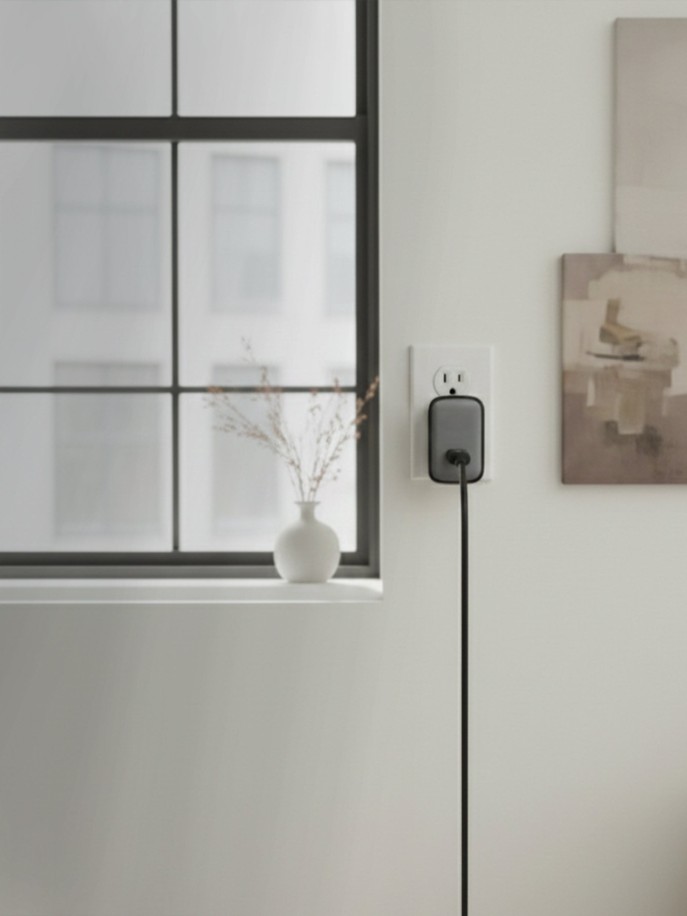 Schlüssel wall charger plugged into a power outlet in a modern minimalist interior
